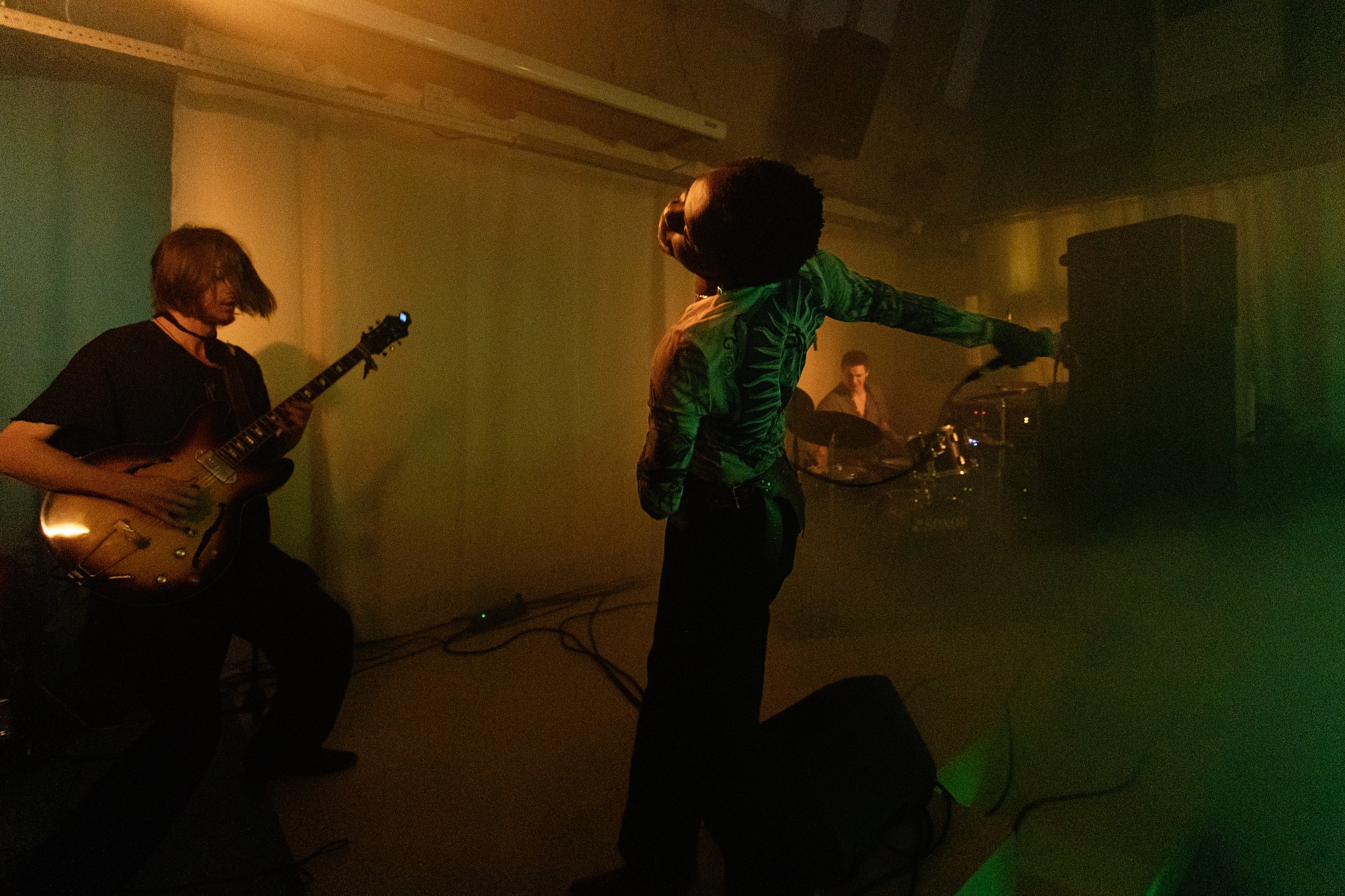 Musical performance with a singer, guitarist and drummer. None of them look into the camera, but are immersed in the live performance.
